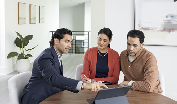 A man showing a young couple something on his tablet