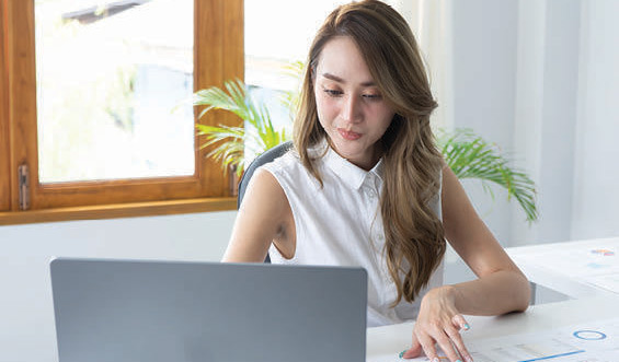 A woman smiles while looking at a computer.