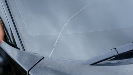 Crack running across a car windshield near the wiper blade.