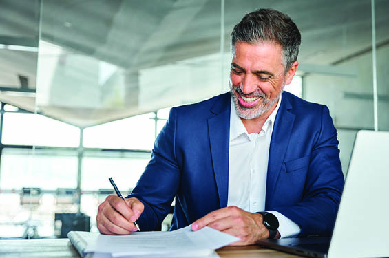 man smiling and writing on a document