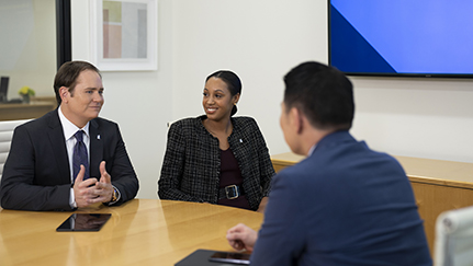 A financial professional speaking with a couple and all are seated around a table