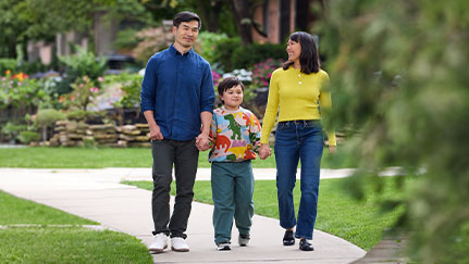 Parents on a walk jointly holding hands with their daughter.
