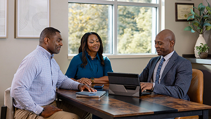 a man and woman sitting around a desk and meeting with a financial advisor