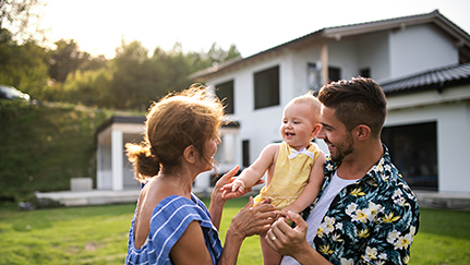 Father holding his child in front of a home