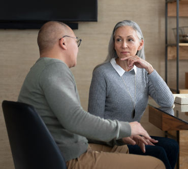 A middle aged married couple discusses retirement planning options in their financial professional’s office.