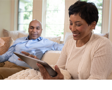 A middle aged woman researches retirement planning options on her tablet and tells her husband what she has learned.