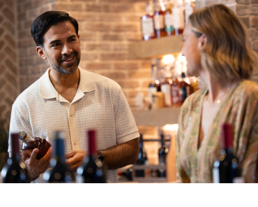 A middle aged married couple selects a wine from their wine cellar.