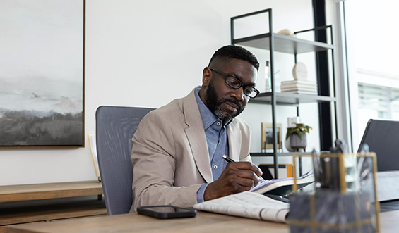 Man writing in a notebook at a desk.