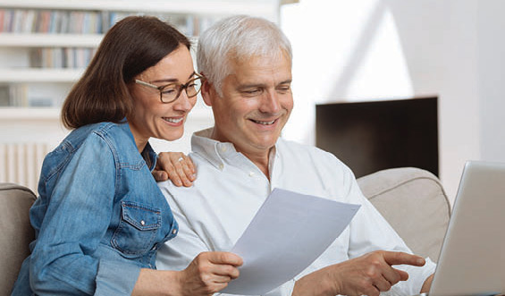 A couple sitting on a couch reviewing their finances