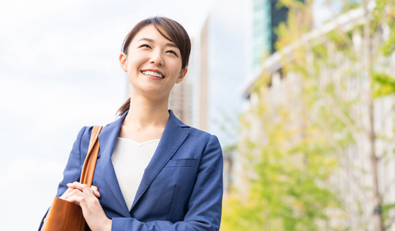 A woman standing outside, smiling while looking into the air.