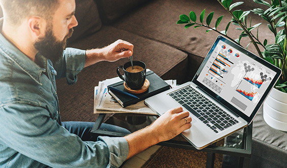 Man sitting at laptop while stirring coffee