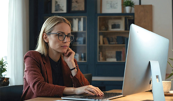 woman sits at desk and scrolls computer