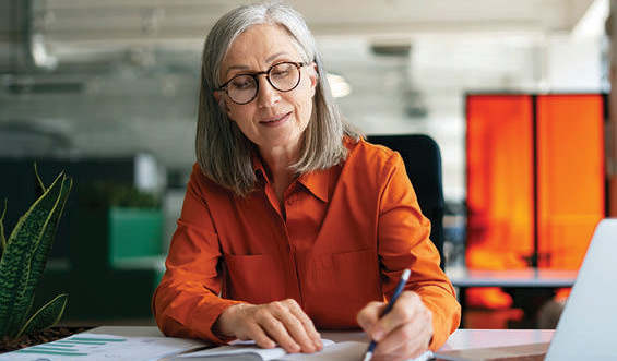 A senior woman writes in an office.