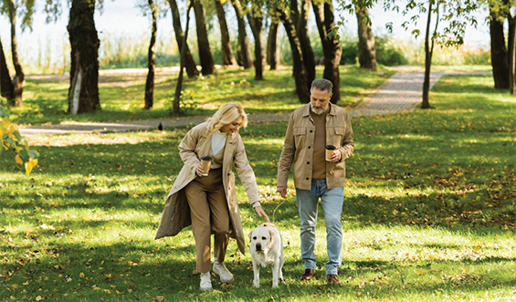 Woman and man with dog in a grassy area.