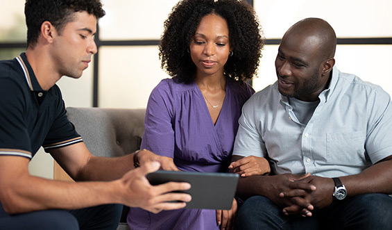 A person showing information on this tablet to a couple.