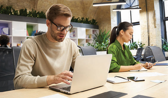 A man and woman work at a table in an office.