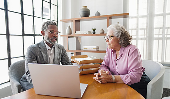 A financial advisor speaking with a woman behind a computer in an office.