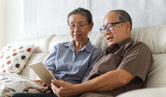 An elderly couple sharing a tablet device.