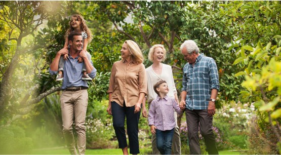 A multi-generational family walking in a verdant garden.